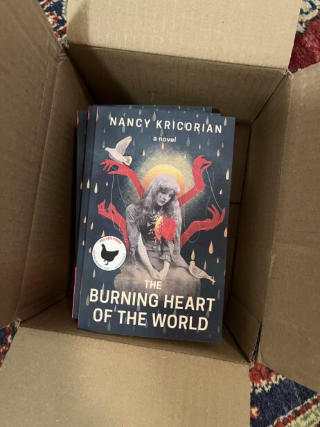 Advanced Readers Copies of the novel THE BURNING HEART OF THE WORLD in a cardboard box